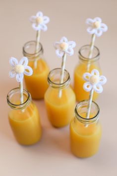 four jars filled with orange juice and white flowers