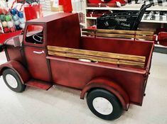 an old fashioned red truck is parked in a store with other items on the shelves