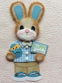 a stuffed animal rabbit holding a happy easter sign on a pink and white wallpapered background