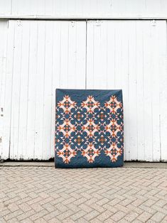 a blue and orange quilt sitting in front of a white building