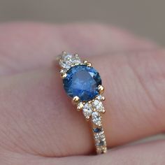 a woman's hand holding a blue and white ring with diamonds on top of it