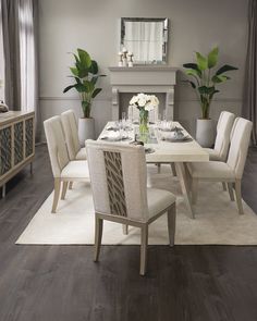 a dining room table and chairs with white flowers in vases on the centerpiece