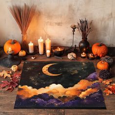 a table topped with candles and pumpkins next to a painting on top of a wooden floor