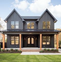 a large gray house with lots of windows on it's front porch and covered patio