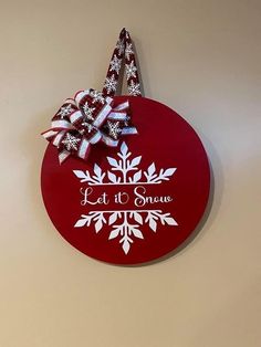 a red sign with white snowflakes on it and a bow hanging from the front