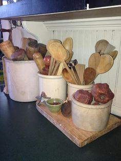 several pots with spoons and wooden utensils in them on a counter top