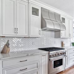 a kitchen with white cabinets and stainless steel stove top oven, range hood, and wooden flooring