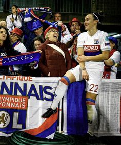 a group of people standing next to each other in front of a crowd holding flags