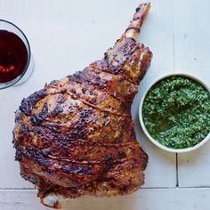 a large piece of meat sitting on top of a table next to a bowl of pesto