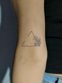 a woman's arm with a small flower tattoo on the left side of her arm