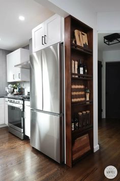 a kitchen with white cabinets and stainless steel refrigerator freezer combo in the corner, next to an open book shelf filled with books