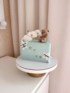 a small teddy bear sitting on top of a blue cake with stars and moon decorations