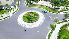 an aerial view of a circular garden in the middle of a road with cars driving on it