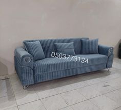 a blue couch sitting on top of a tile floor next to a white tiled wall