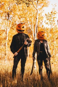 two people wearing pumpkin hats and holding bats