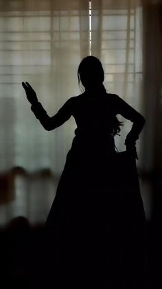 the silhouette of a woman standing in front of a window