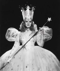 an old photo of a woman in a princess costume holding a wand and wearing a tiara