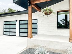 a white house with black garage doors and a planter hanging from the front porch