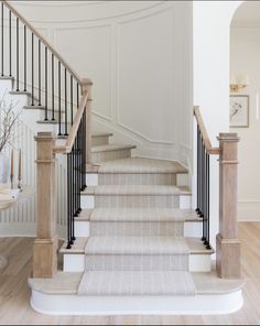 there is a white staircase with beige carpet and black railings on the second floor