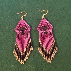 pink and black seed beaded earrings on green carpeted floor with gold earwires