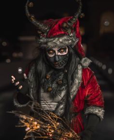 a man dressed up as a demon with horns and makeup holding a sparkle ball in his hand