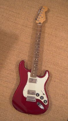 a red electric guitar laying on top of a couch