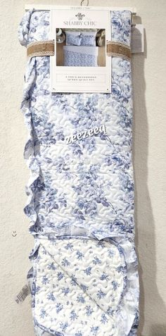 a blue and white blanket hanging on the side of a wall next to a pair of scissors