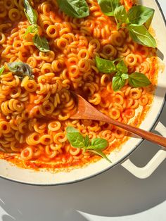 a pot filled with pasta and basil on top of a table