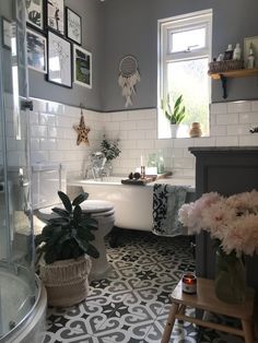 a bathroom with black and white tile flooring and pictures on the wall above the tub