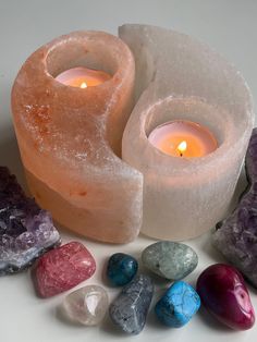 some rocks and candles sitting on a table with one candle lit in the middle, surrounded by them