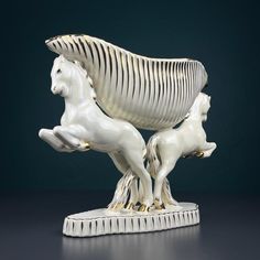 a white horse and foal sculpture sitting on top of a black table next to each other