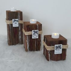 three candles are wrapped in twine and tied to wooden blocks with tags on them