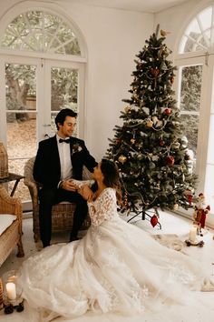 a bride and groom sitting in front of a christmas tree