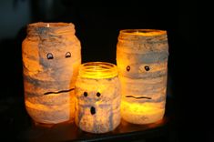 three lit up jars with faces on them