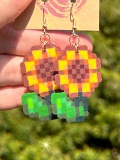 a pair of earrings made out of legos is being held by someone's hand