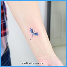 a small tattoo on the wrist of a woman's left arm, with two blue bats