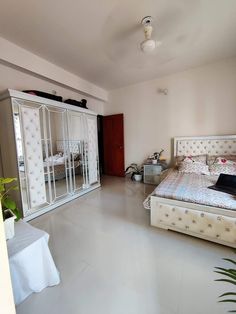 a bed room with a neatly made bed next to a white dresser and mirror cabinet