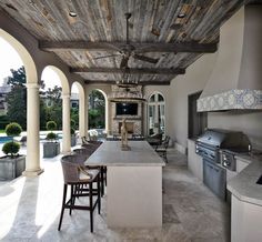 an outdoor kitchen and dining area with stone counter tops, wood ceilinging, and fireplace