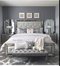 a bedroom with gray walls and white bedding, mirrored headboard and foot board