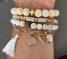 a woman's arm with three bracelets and two cross charms on the wrist