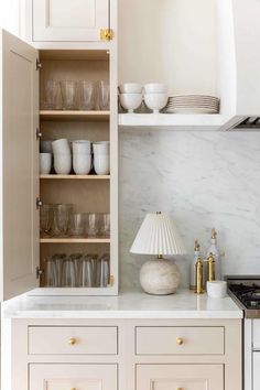 a white kitchen with marble counter tops and gold pulls on the cabinet doors is shown