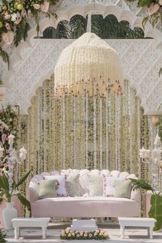 a white couch sitting under a chandelier covered in flowers