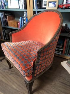 an orange chair sitting in front of a book shelf