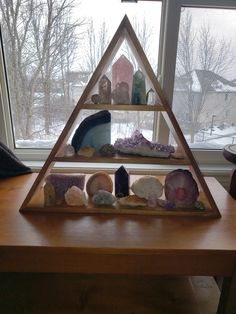 a wooden table topped with three pyramids filled with different types of rocks and crystals