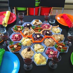 a black table topped with plates and bowls filled with different types of food next to wine glasses