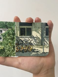 a person holding up a small book with pictures on the front and back cover in their hand