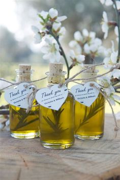 three bottles filled with olive oil sitting on top of a wooden table