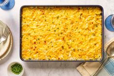 a casserole dish with cheese and herbs on the side next to silverware