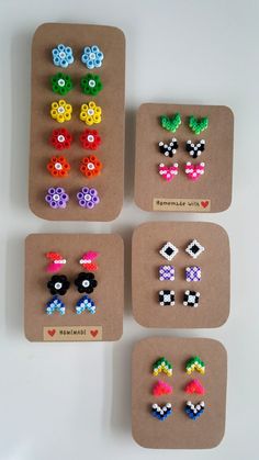 four pairs of earrings made out of small beads are displayed on a piece of cardboard