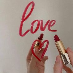 two hands holding lipstick and writing the word love